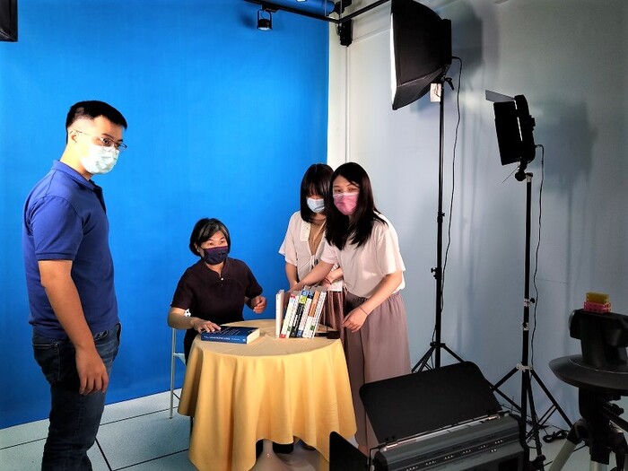 黃鳳英老師與錄影小組人員調整書籍擺設。(111.8.1)